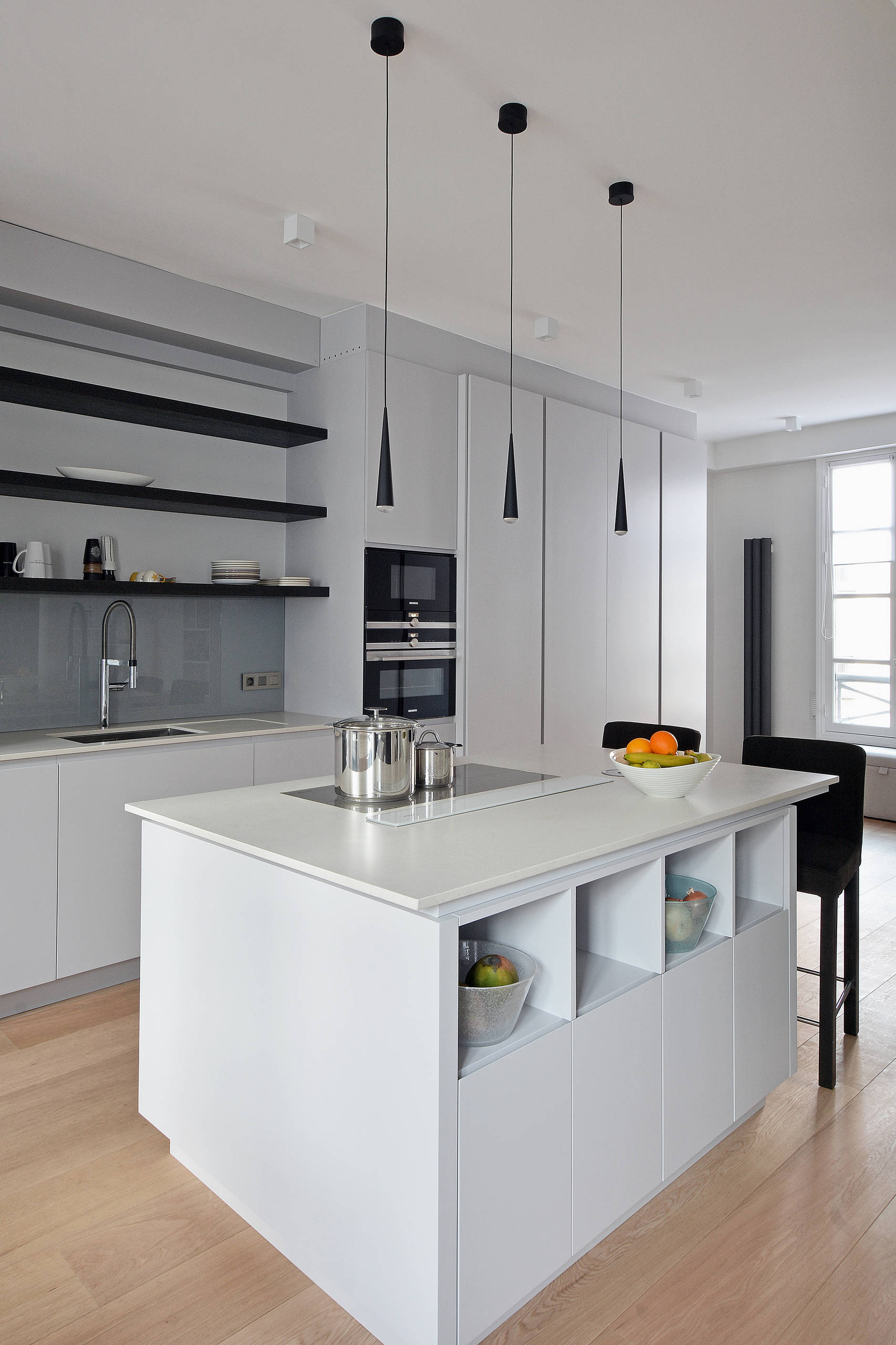 Cuisine contemporaine blanche avec îlot central, piliers de structure métallique et étagères noires — Paris 6e