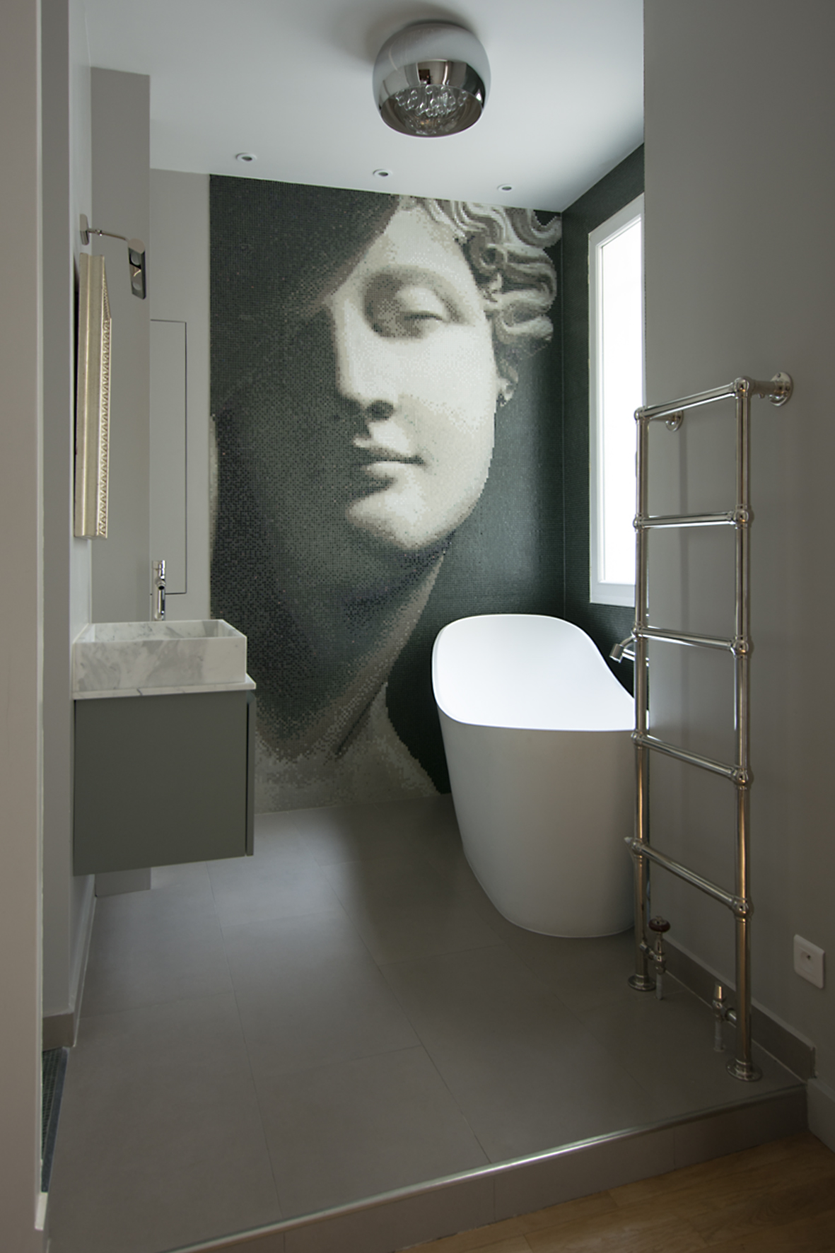 Baignoire îlot blanche devant fresque mosaïque grise — salle de bain haut de gamme Paris 7e