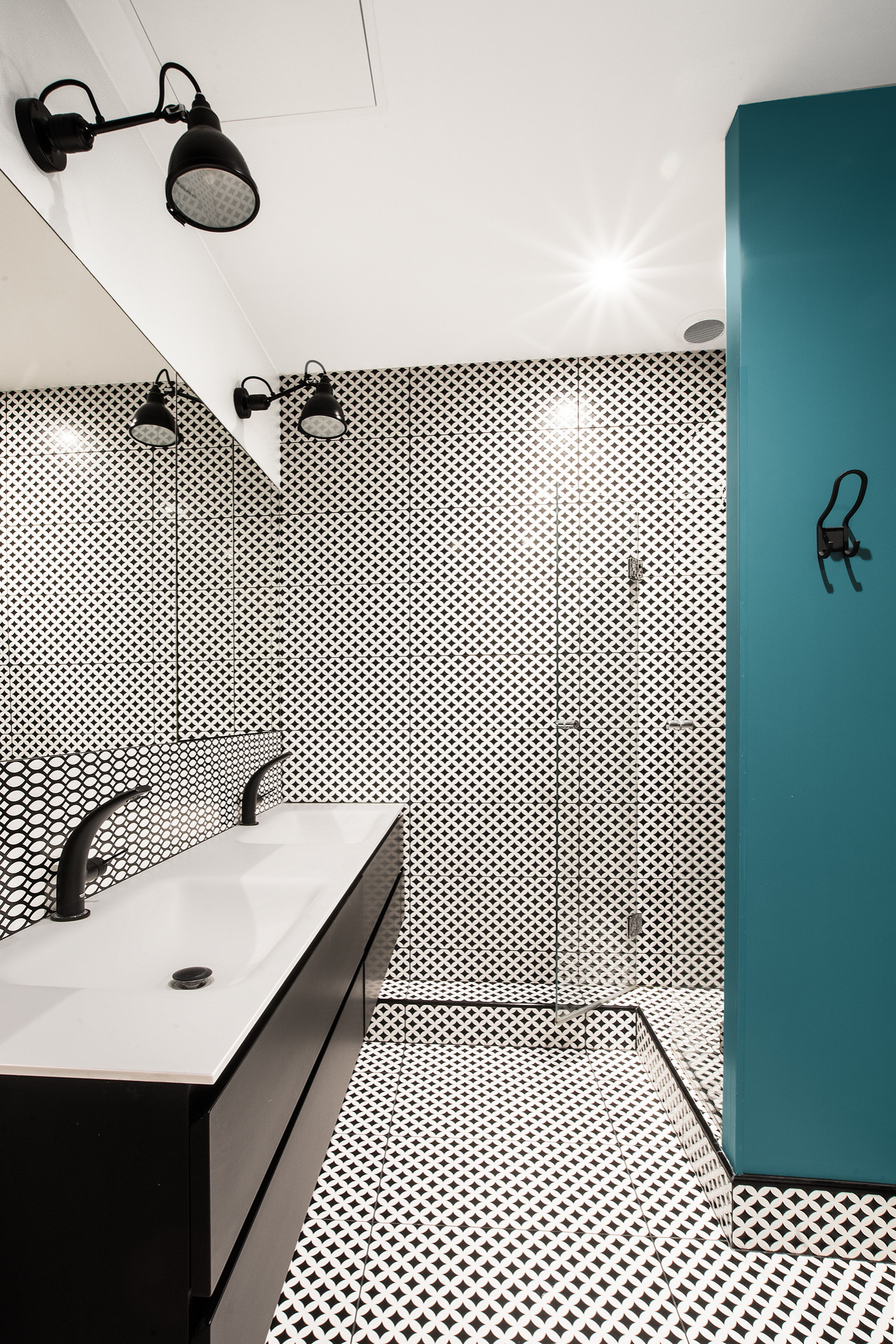 Salle de bain graphique avec carreaux ciment noir et blanc, douche italienne et colonne bleu canard — appartement haussmannien Paris 7e