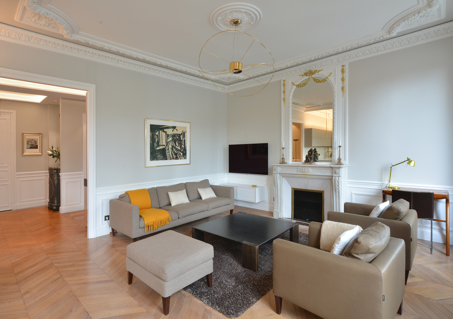 Salon avec canapé, cheminée marbre et parquet chevron — appartement haussmannien Paris